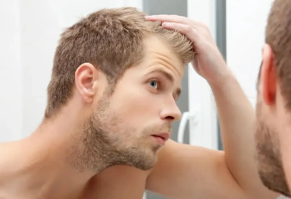 A man with his hand on his head looking at the camera.