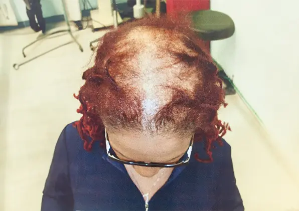 A woman with red hair and glasses in front of a mirror.