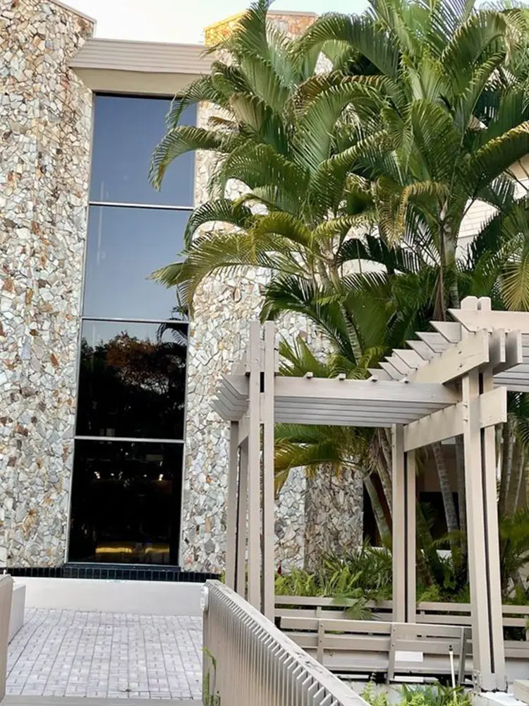 A building with a large window and palm trees.