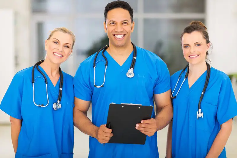 Three doctors are standing together in a hospital.